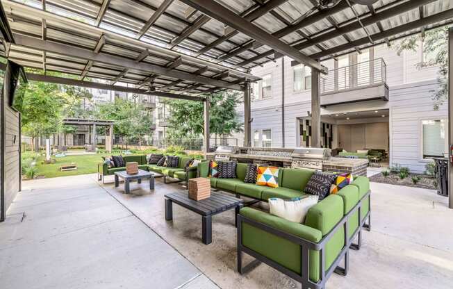 a patio with green couches and tables and a building in the background