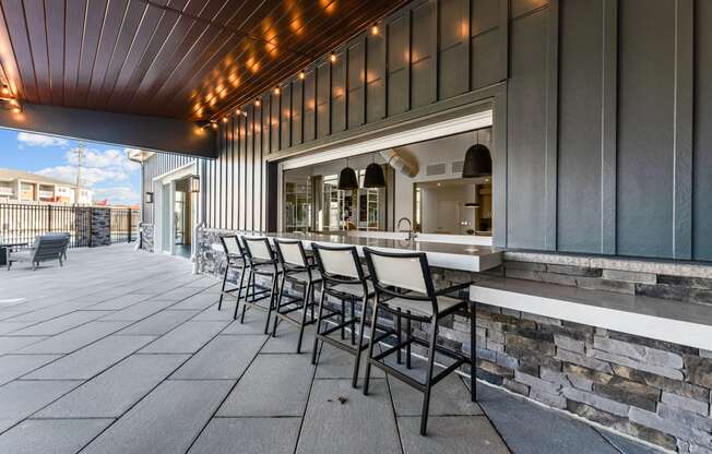 a patio with a bar and chairs in front of a building
