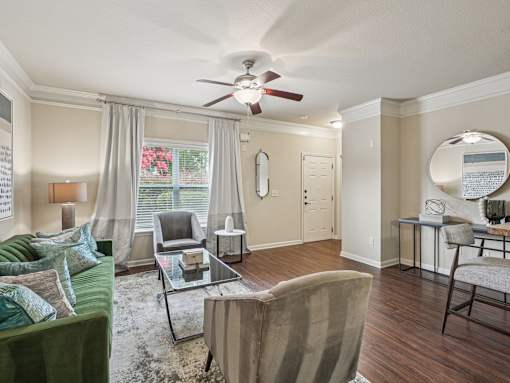 A living room with a green couch and a glass coffee table.