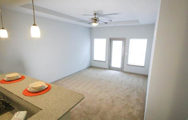 Living room view with a counter, ceiling fan, two windows and a door at Mosaic Apartments in Avon, Indiana