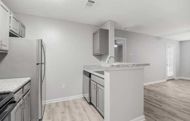 the spacious kitchen with stainless steel appliances and white countertops