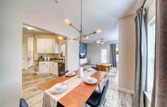 a dining area with a wooden table and chairs and a kitchen in the background at Meridian Obici, Suffolk, VA
