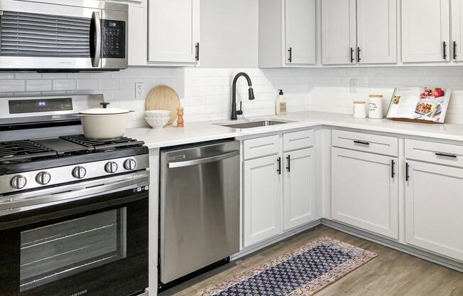 a kitchen with white cabinets and stainless steel appliances  at Sunset Heights, Texas