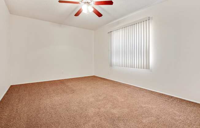 Bedroom with ceiling fan and carpeted floors, vertical window blinds on the right