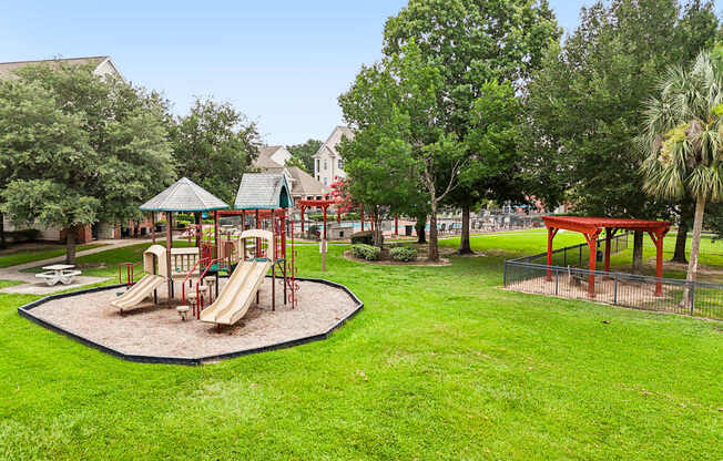 A playground with a red slide and a green lawn.