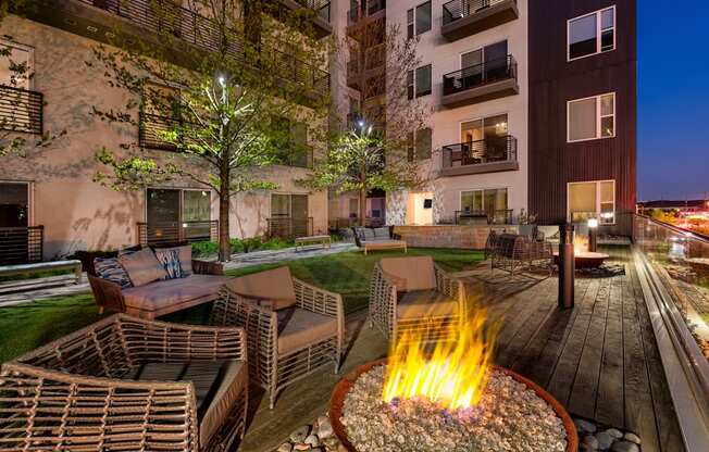 A fire pit in the middle of a patio surrounded by chairs.