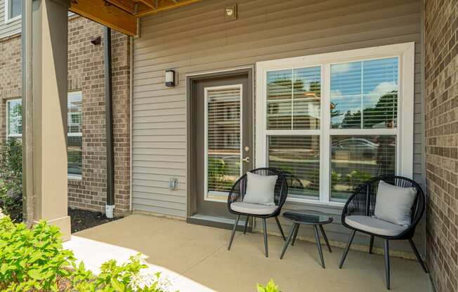a patio with two chairs and a table on a porch