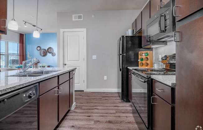 A kitchen with brown cabinets and a black refrigerator.
