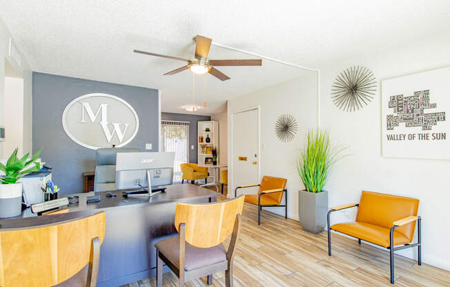 a living room with a desk and chairs and a ceiling fan