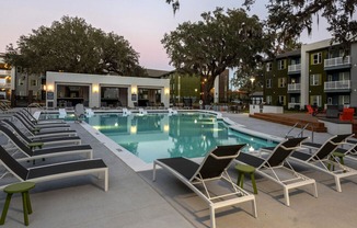 A poolside area with lounge chairs and a building in the background.