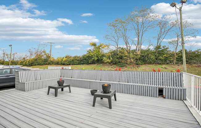 A wooden deck with two benches and a table.