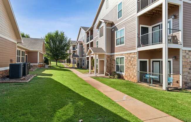 A sunny day at a residential apartment complex with a well-maintained lawn and pathway.