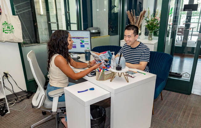 a man and a woman sitting at a desk in front of a computer