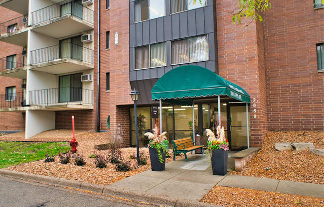 A building with a green awning and potted plants in front.