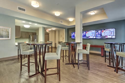 a common area with tables and chairs and a large screen tv