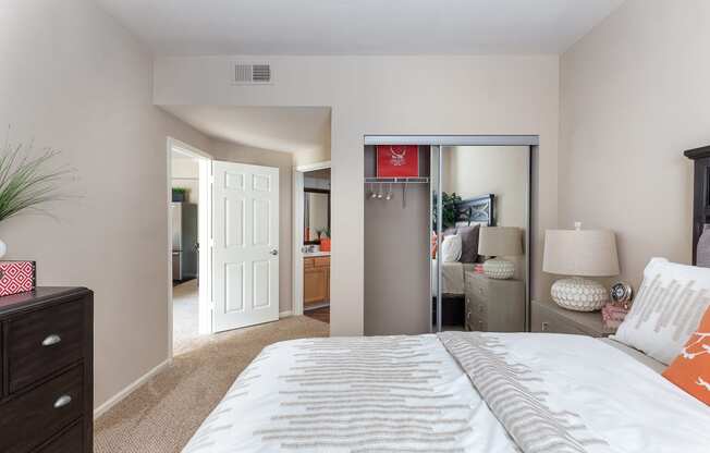 1, 2, & 3-BR Apartments in Overland Park, KS - The Highlands - Bedroom With Carpeting, Full-Size Bed, Dresser, Mirror Closet Door, And Bathroom Entrance