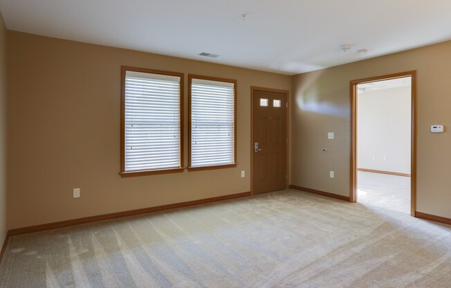 an empty living room with a door and windows