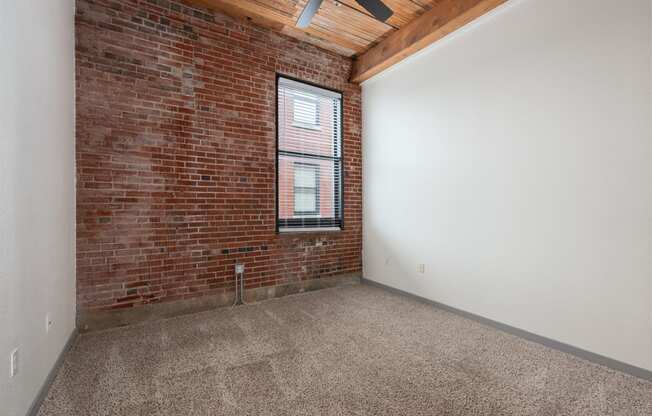 an empty room with a brick wall and a window