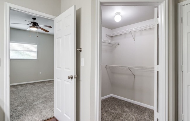 an empty closet with a ceiling fan and a white closet door