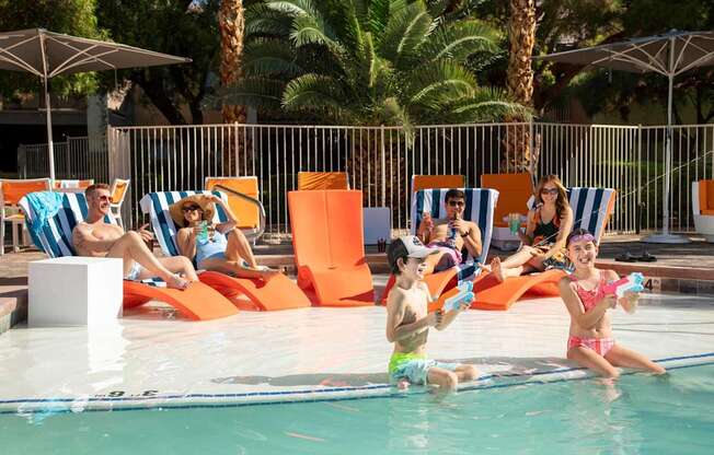 People are relaxing by the poolside on sun loungers.