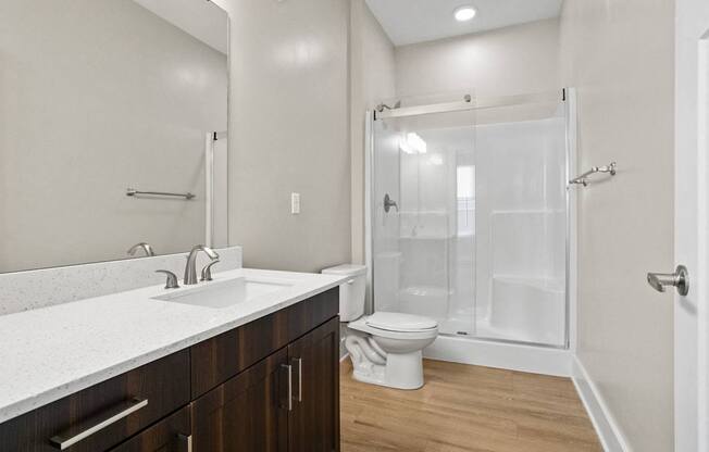 A white bathroom with a toilet, sink, and shower.