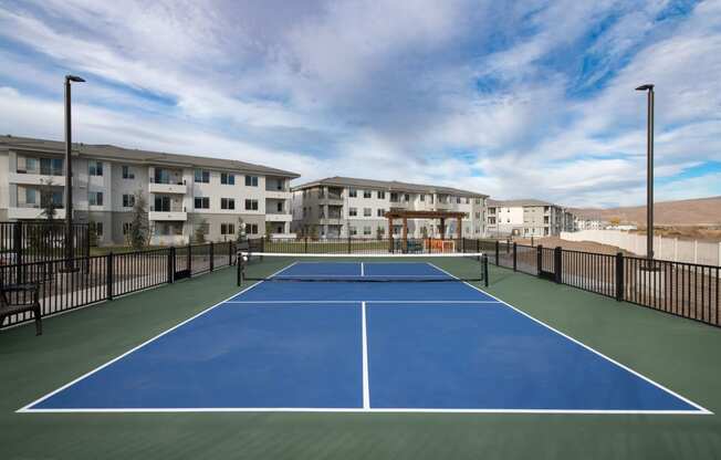 a pickleball court with apartments in the background
