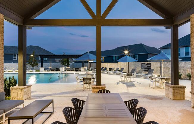 An open-air pool pavilion at Amavi Celina with communal tables, shaded seating, and evening lighting that sets an inviting tone for outdoor gatherings.