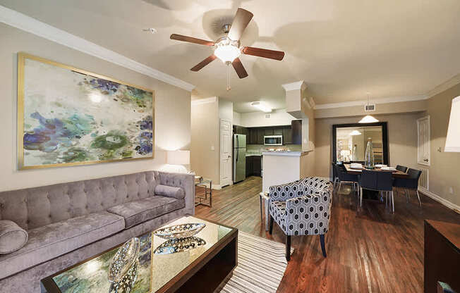 A living room with a grey couch and a painting on the wall.
