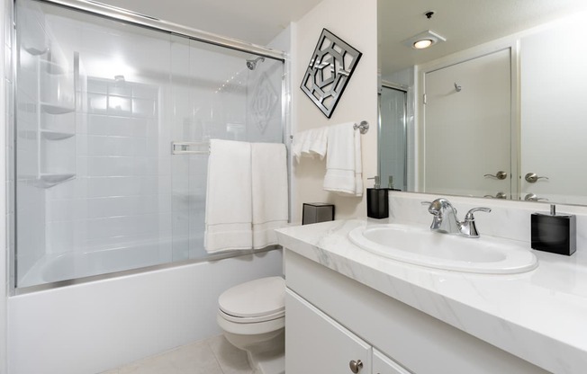 A white bathroom with a toilet, sink, and shower.