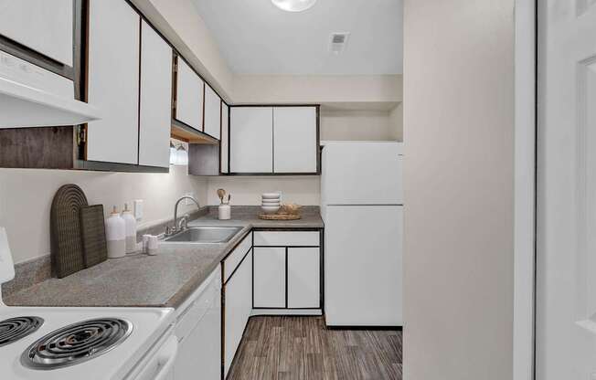 A kitchen with white cabinets and a wooden floor.