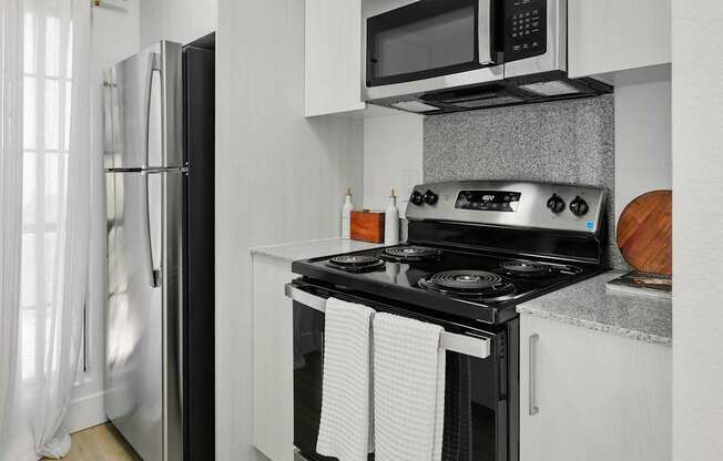 A modern kitchen with a black stove top oven and white cabinets.