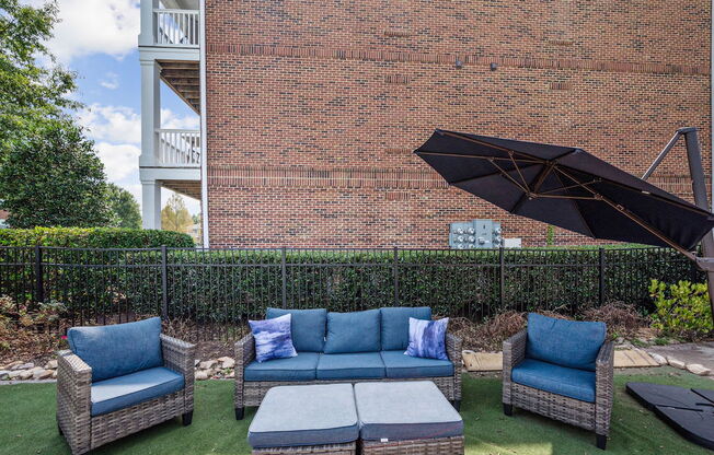 a patio with couches and chairs in front of a brick building