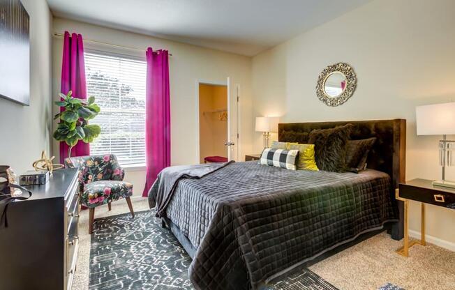 Apartments for Rent in San Antonio, TX - Club at Stone Oak - Bedroom with Plush Carpet Flooring, a Bed, Chair, Dresser, Nightstands, Lamps, Closet, and Window