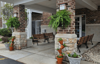 a porch with benches and potted plants in front of a building