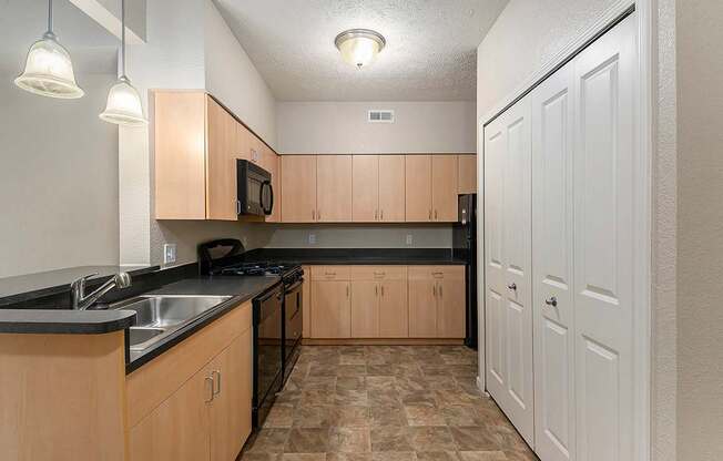 A kitchen with black countertops and wooden cabinets at Lynbrook Apartments and Townhomes, Elkhorn, NE, 68022