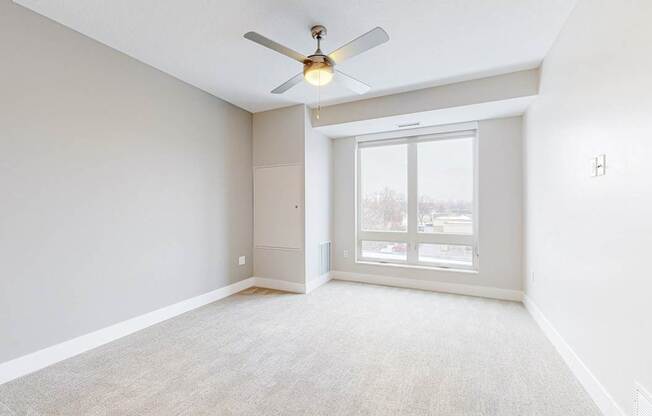 A room with a ceiling fan and a sliding glass door.