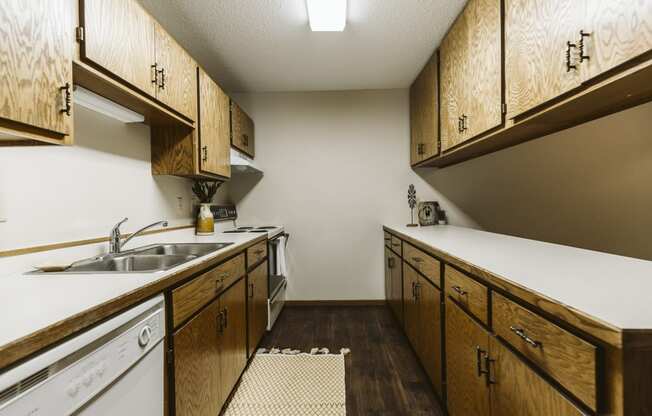 Grand Forks Harrison Apartments. kitchen with wooden cabinets and white appliances and a sink