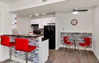 A kitchen with a bar area and red chairs at Urban WalkApartments on 6th Avenue, Phoenix