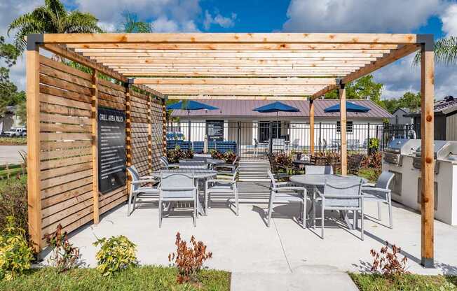 A wooden pergola with a sign and chairs under it.