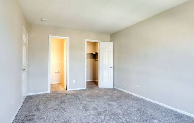 an empty living room with carpet and a door to a closet at Bayville Apartments, Virginia Beach, VA