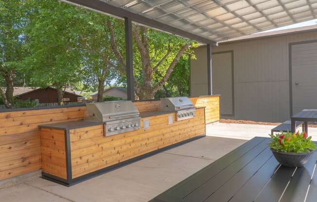 an outdoor kitchen with a wooden facade and a wooden table with a potted plant