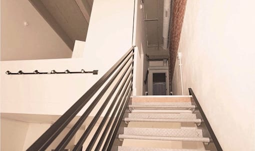 a set of stairs leading up to a hallway with a railing and a white wall