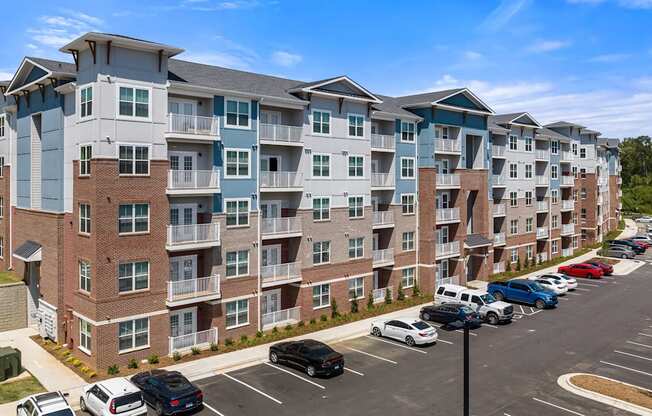 A large apartment complex with a parking lot in front.