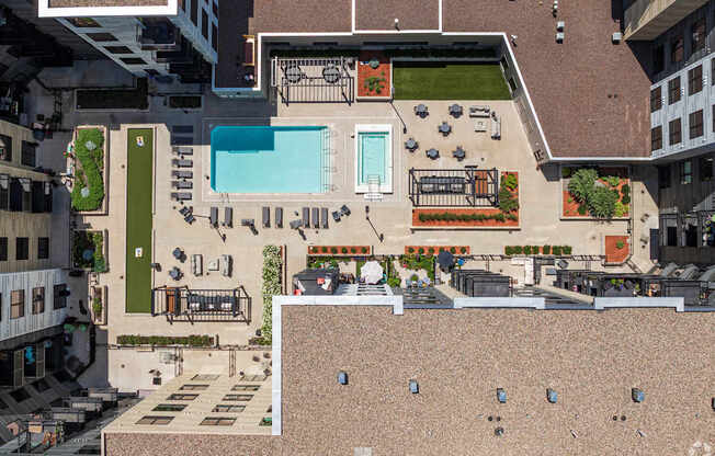 A rooftop patio with a pool and a table with chairs.