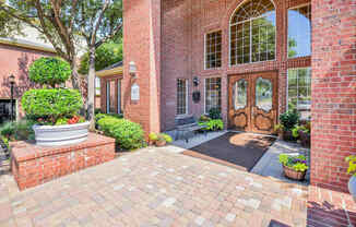 Gates de Provence leasing office entrance with two large double doors is surrounded by florals and greenery!