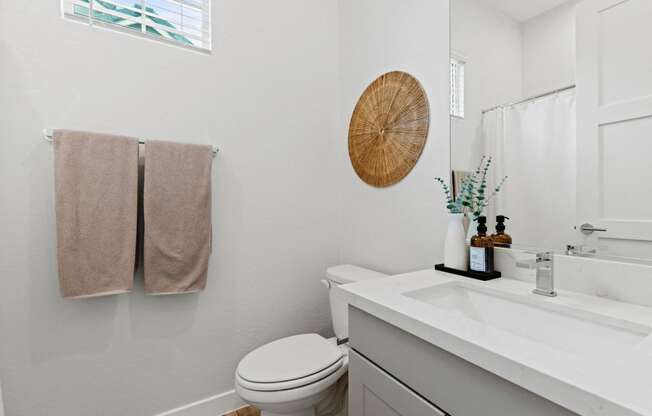 a bathroom with a toilet and a sink and a mirror at Village of Chandler Apartments, Arizona, 85249