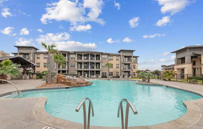 A large swimming pool in front of a building with a clear blue sky above.