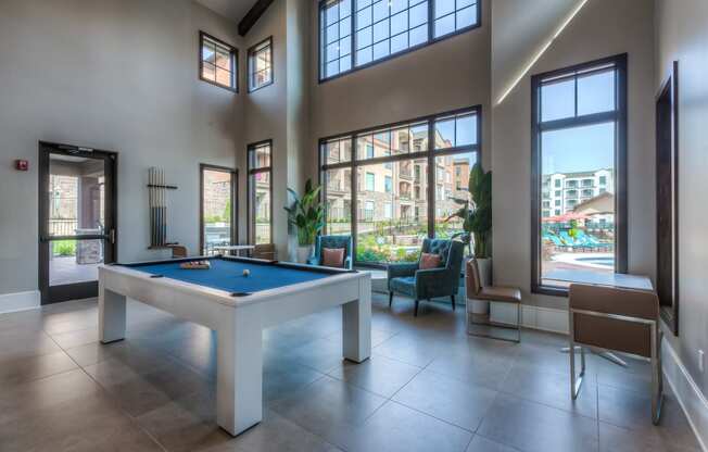 a pool table in the clubhouse with floor to ceiling windows