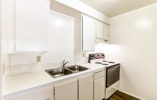 a small kitchen with white cabinets and a stove and sink