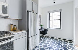 kitchen with white cabinetry, stainless steel appliances, microwave and built in desk at the dahlia apartments in washington dc